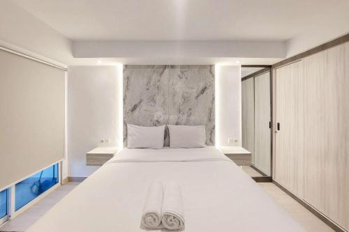 メダンにあるSimply Look Studio Apartment at Mansyur Residence By Travelioの白い枕が付いた大きな白いベッドのある寝室