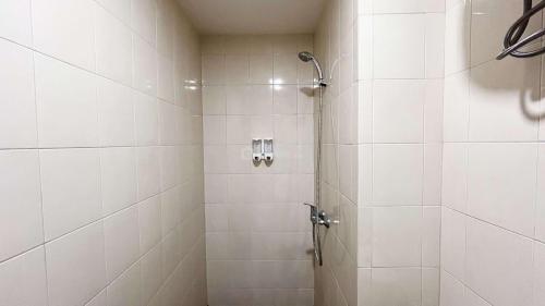 PampangにあるBest Price 2BR Apartment Vida View Makassar By Travelioの白いタイルのシャワー付きのバスルーム