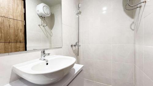 a white bathroom with a sink and a shower at Good Choice Studio at Delft Ciputra Makassar Apartment By Travelio in Sungguminasa