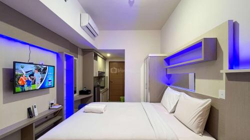a bedroom with a bed with a tv on the wall at Best Choice Studio Apartment at Vida View Makassar By Travelio in Pampang