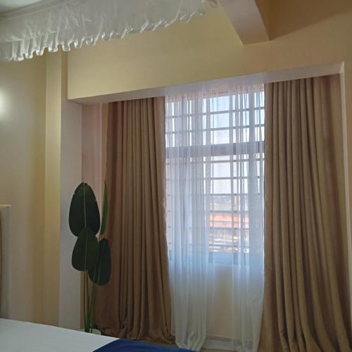 a bedroom with a large window with curtains at Zane's cabin in Nyeri