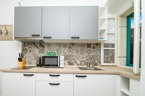 a kitchen with white cabinets and a microwave at Holiday house Nerezine in Nerezine