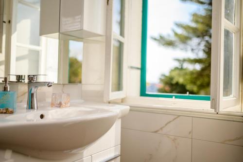 a white bathroom with a sink and a window at Holiday house Nerezine in Nerezine