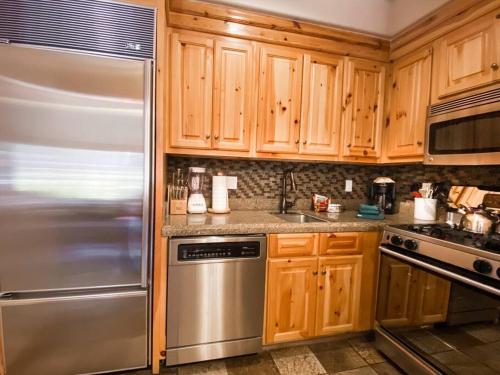 a kitchen with wooden cabinets and a stainless steel refrigerator at 2 BR Condominium - Luxury Skiin and out (rare to find) in Telluride