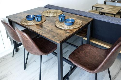 een houten tafel met vier stoelen en blauwe kopjes erop bij F4 - La Maison de M Goéland - 4e etage in Le Havre