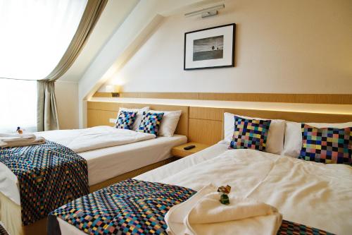 two beds in a hotel room with a teddy bear sitting on top at Hotel Great Polonia Velvet Suwałki in Suwałki
