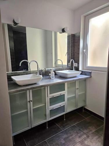 une salle de bain avec deux lavabos et un grand miroir dans l'établissement Carcassonne tranquillement, à Carcassonne