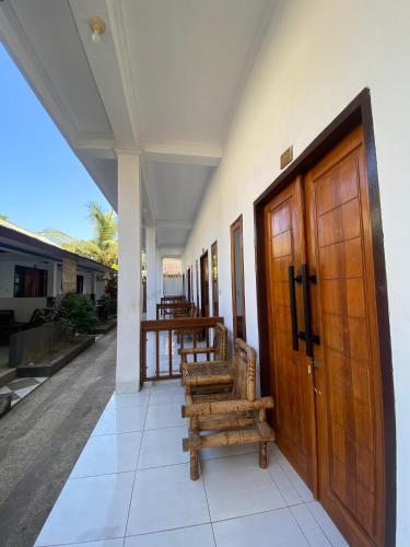 un porche de una casa con puertas y bancos de madera en Bale sunrise, en Gili Trawangan