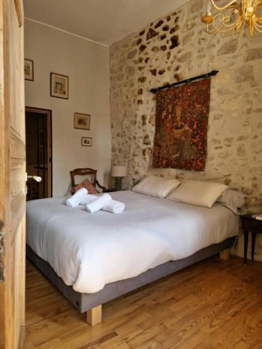 ein Schlafzimmer mit einem großen Bett mit einer Steinwand in der Unterkunft Le Presbytère de Maître Jacques in Arles