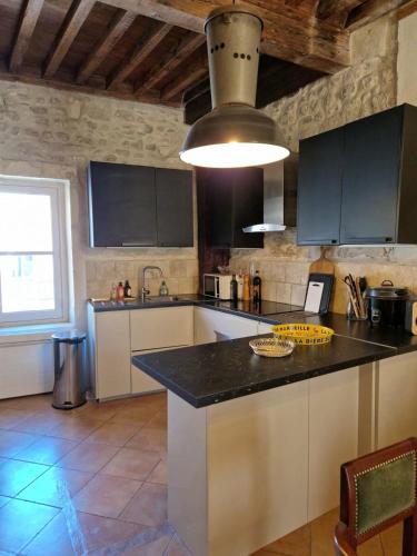 une cuisine avec un comptoir noir dans une pièce dans l'établissement Le Presbytère de Maître Jacques, à Arles