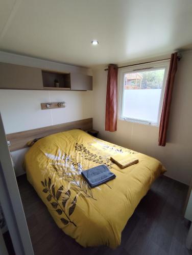 une chambre avec un lit jaune avec une fenêtre dans l'établissement MOBIL HOME 40M2 ECRIN DE VERDURE, à Rocbaron