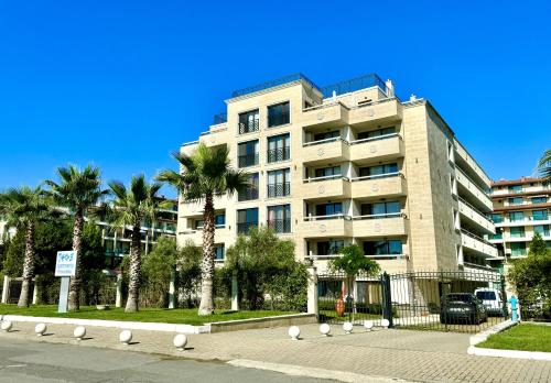 a building with palm trees in front of a street at Teos Apartments Primorsko in Primorsko