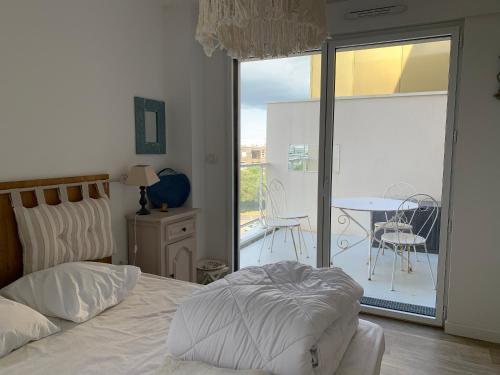 une chambre avec un lit et un balcon avec une table dans l'établissement appt Grand Voile, à La Rochelle