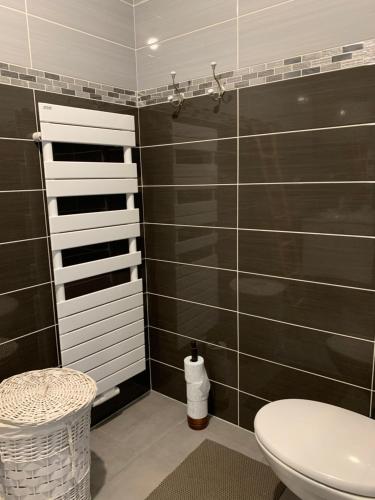La salle de bains est pourvue de toilettes et d'un mur carrelé noir. dans l'établissement appt Grand Voile, à La Rochelle