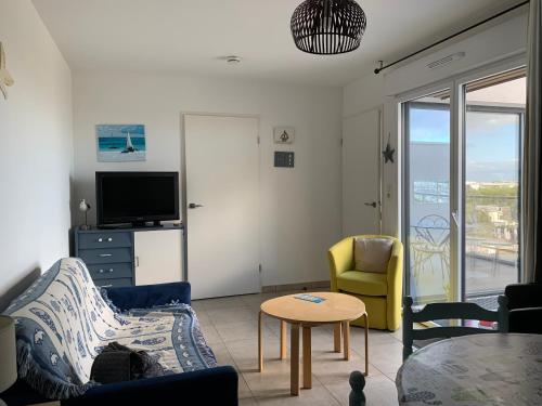 un salon avec un canapé, des chaises et une télévision dans l'établissement appt Grand Voile, à La Rochelle