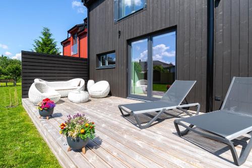 a wooden deck with two chairs and flowers on it at Posti villa in Pärnu