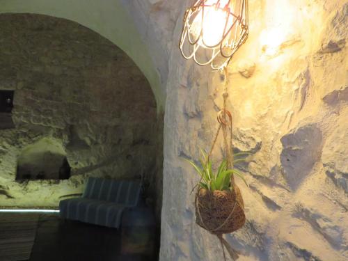 a chandelier hanging from a stone wall with a couch at la Postierla in Modica