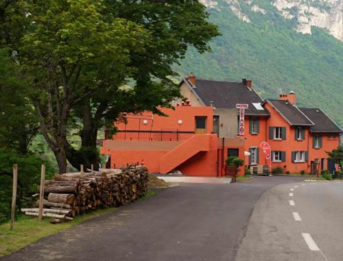 an orange building with a pile of logs on the side of a road at Picasso Chambre Privée Le Refuge Du Phoenix in Échevis