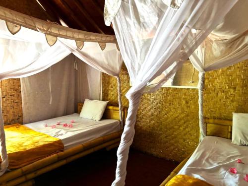 a bedroom with two beds with white curtains at Dessert Point Bungalow in Sekotong