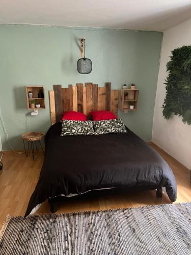 - une chambre avec un grand lit noir et des oreillers rouges dans l'établissement Maison de ville au cœur de la Provence, à Sérignan-du-Comtat
