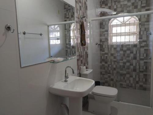 a bathroom with a sink and a toilet and a mirror at Casa Itaguá in Ubatuba