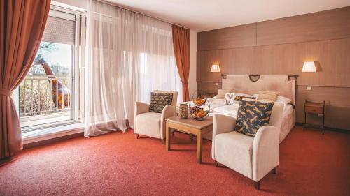 a hotel room with a bed and chairs and a window at Malkia Penzion in Orechová Potôň