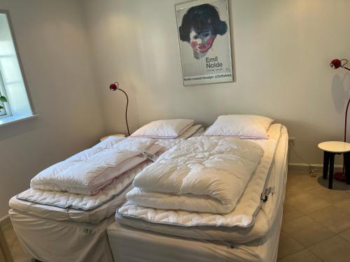two beds in a room with a dog picture on the wall at Ferielejlighed in Nørre Åby