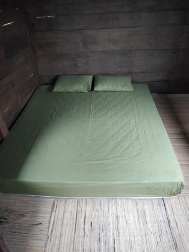 a green bed in a room with a wooden floor at Sang Natha Lodge in Tjatur