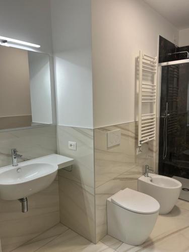 a white bathroom with a sink and a toilet at Beach Palace with small swimming pool, private beach, parking in Lido di Jesolo