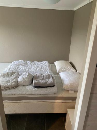 a bed with white sheets and pillows on it at Ingvilds hybelleilighet in Kristiansand
