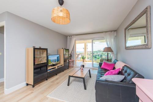 un salon avec un canapé et une télévision dans l'établissement BEAUSEJOUR - Splendide 2 pièces - Piscine - Parking - Vue mer, à Beausoleil