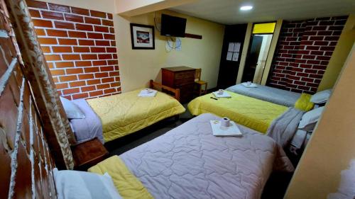 a room with three beds and a brick wall at Mirador Backpackers B&B in Huaraz