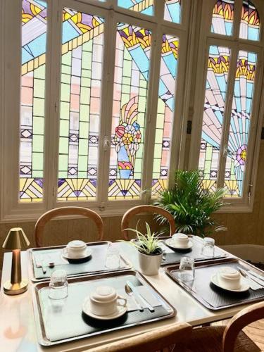 a dining room with a table and a stained glass window at Hôtel De Normandie in Amiens