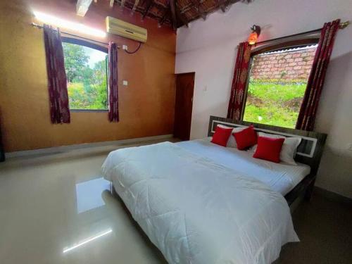 a bedroom with a bed with white sheets and red pillows at The Pearly Gates Twin Villa in Dande