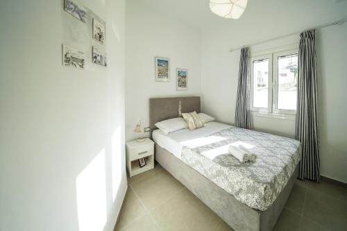 a white bedroom with a bed and a window at Dream Santo Villa in Vóthon