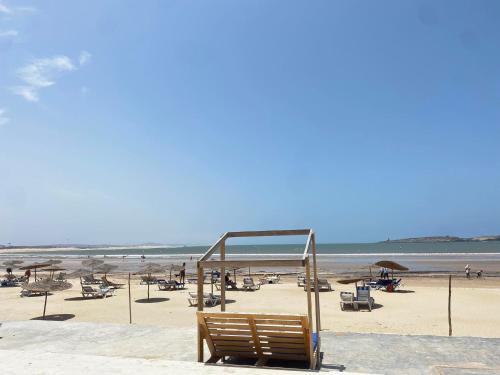 a bench on a beach with chairs and umbrellas at Tarbouche on the Beach in Essaouira
