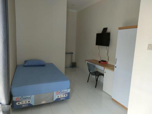 a bedroom with a bed and a desk and a television at MJhuis Female Homestay in Salakan