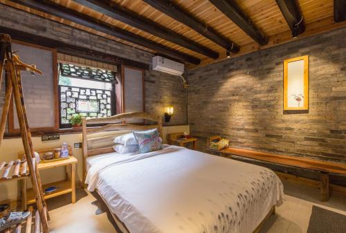 a bedroom with a bed and a brick wall at Governor's Mansion in Yangshuo