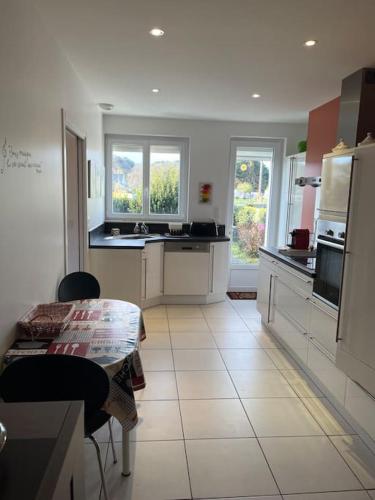 une cuisine avec des armoires blanches et une table à l'intérieur dans l'établissement Maison proche du bord de mer, à Riantec