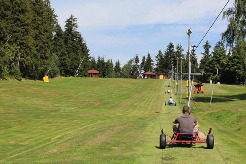 a man riding a red car in a field at Apartmán Resident A001 - BEZBARIÉROVÝ Apartmán ideální pro rodiny s dětmi, v těsné blízkosti Anenského údolí, bobové dráhy, Ski areálů, Ski školy, FREE PARKING, FREE WIFI, výhled do zahrady s posezením na terase, dětské hřiště v areálu in Harrachov