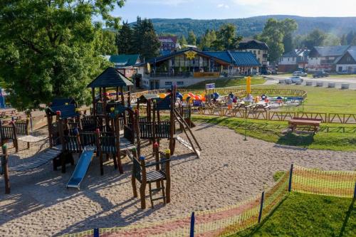 a park with a playground with a slide at Apartmán Resident A001 - BEZBARIÉROVÝ Apartmán ideální pro rodiny s dětmi, v těsné blízkosti Anenského údolí, bobové dráhy, Ski areálů, Ski školy, FREE PARKING, FREE WIFI, výhled do zahrady s posezením na terase, dětské hřiště v areálu in Harrachov