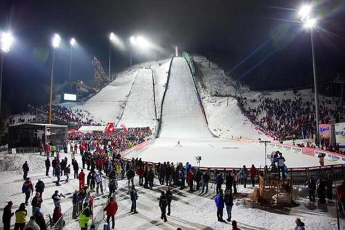 a crowd of people standing around a ski slope at night at Apartmán Resident A001 - BEZBARIÉROVÝ Apartmán ideální pro rodiny s dětmi, v těsné blízkosti Anenského údolí, bobové dráhy, Ski areálů, Ski školy, FREE PARKING, FREE WIFI, výhled do zahrady s posezením na terase, dětské hřiště v areálu in Harrachov