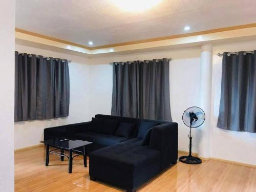 a living room with a black couch and a table at Fully furnished 3 Bedrooms 2 storey House!! in Dipolog