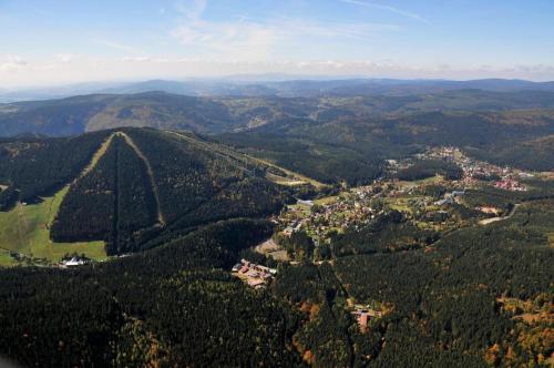 an aerial view of a town in a forest at Apartmán Resident A001 - BEZBARIÉROVÝ Apartmán ideální pro rodiny s dětmi, v těsné blízkosti Anenského údolí, bobové dráhy, Ski areálů, Ski školy, FREE PARKING, FREE WIFI, výhled do zahrady s posezením na terase, dětské hřiště v areálu in Harrachov