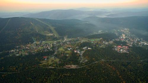an aerial view of a town in the mountains at Apartmán Resident A001 - BEZBARIÉROVÝ Apartmán ideální pro rodiny s dětmi, v těsné blízkosti Anenského údolí, bobové dráhy, Ski areálů, Ski školy, FREE PARKING, FREE WIFI, výhled do zahrady s posezením na terase, dětské hřiště v areálu in Harrachov
