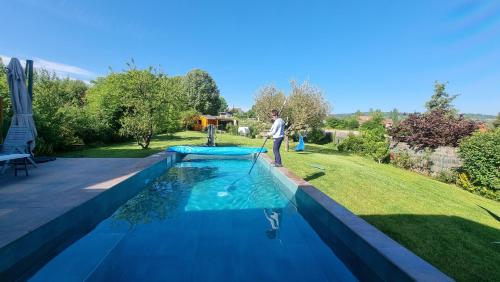 Ein Mann steht neben einem Pool in der Unterkunft Villa avec piscine By Platinum Homes- capacité 10 personnes - Heillecourt in Heillecourt