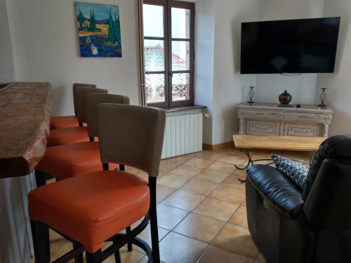 a room with a bar with chairs and a flat screen tv at Le Val Danse - Maison de caractère de 1870 - Rénovée en 2020 in Saint-Anthème
