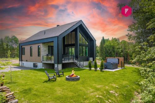 a house with a fire pit in a yard at The Green Chill at Cité-Jardin - Private SPA, Ping pong, Fireplace & Pool in Saint-Basile