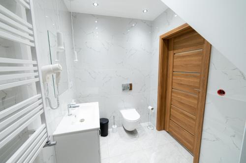 a white bathroom with a toilet and a sink at Ostoja Tatary Agroturystyka in Tykocin