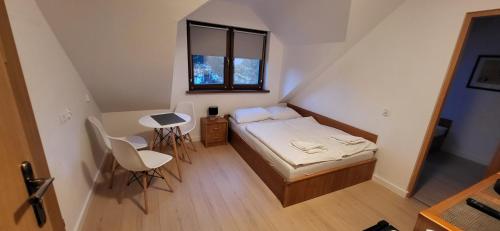 a small bedroom with a bed and a table and chairs at Pensjonat Senya in Niechorze